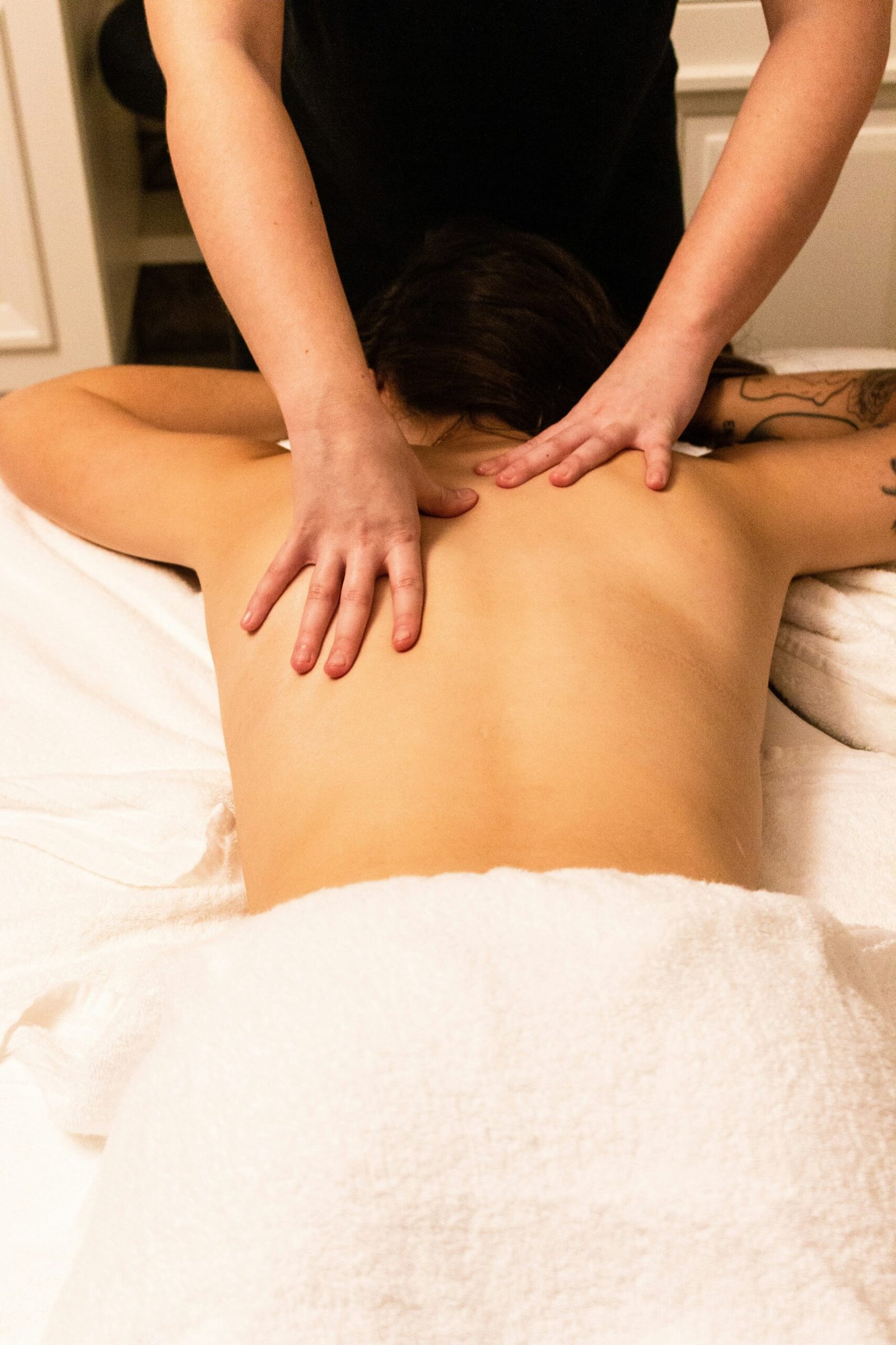 Person receiving a professional back massage while lying face-down on a massage table.